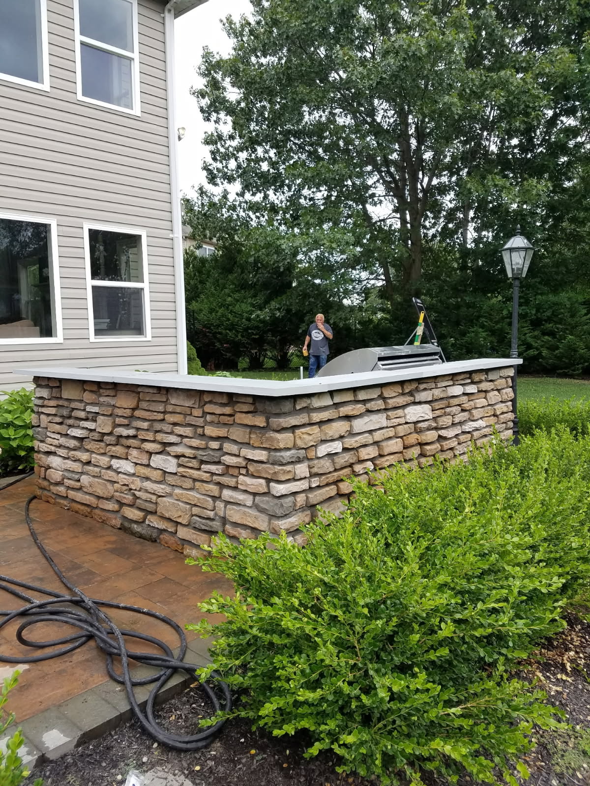 Finished stone veneer wall with a smooth cap enclosing an outdoor kitchen